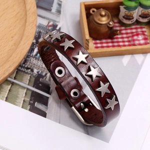 Close-up of vintage brown leather star-studded punk bracelet on a rustic tray