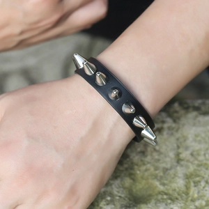 Detail of a punk leather bracelet for men with silver metal spikes on rock background