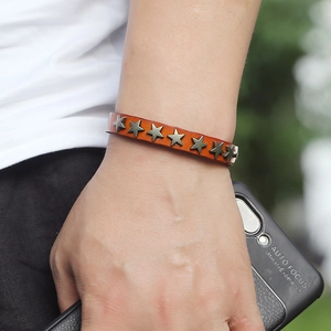 Brown punk leather bracelet with star metal studs worn on wrist for retro style
