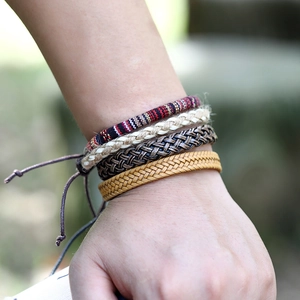 Dettaglio di un set di quattro bracciali multistrato in pelle e tessuto da uomo