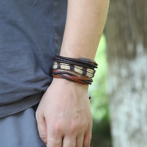 Détail d'un ensemble de bracelets en cuir multicouche vintage sur poignet tressé