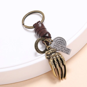 Vintage bronze skeleton hand keychain with woven leather strap and engraved metal charms