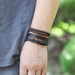 Gros plan de bracelets en cuir tressé multicouche vintage sur un poignet masculin