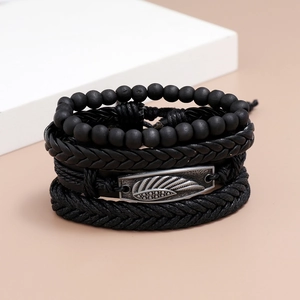 Détail de bracelets multicouches en cuir noir tressé avec breloque aile vintage