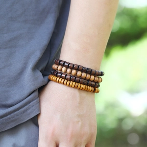Détail de quatre bracelets en perles de bois superposés avec texture naturelle au poignet