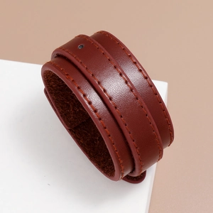 Macro detail of dark brown leather bracelet with fine stitching on minimalist background