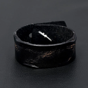 Close-up of wide black cowhide leather bracelet with vintage distressed texture