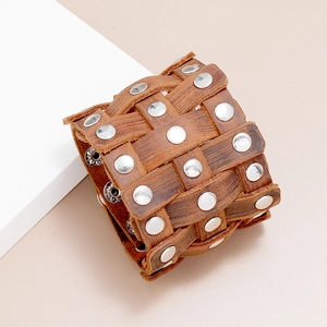 Detail of vintage brown braided leather wristband featuring silver punk metal rivets
