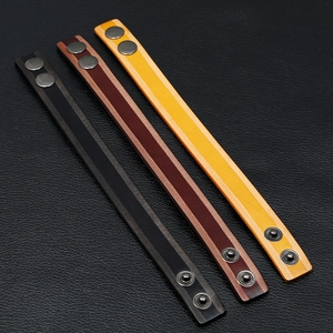 Detailopname van vintage lederen armbanden in zwart, bruin en geel met metalen drukkers