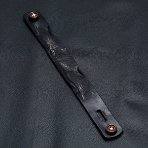 Detailed shot of vintage punk black leather bracelet with antique copper buttons