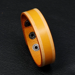 Detail van de gele lederen brede armband met contraststiksel en verstelbare zilveren drukknopen