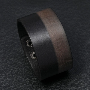 Detail of wide two-tone leather bracelet with dual metal snap closure and smooth edges