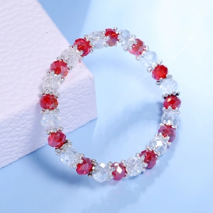 Detalle de una pulsera de cuentas de cristal rojo y transparente en caja violeta