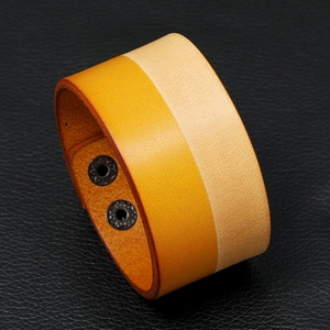 Detailed macro view of two-tone orange and cream wide leather bracelet with metal buckles