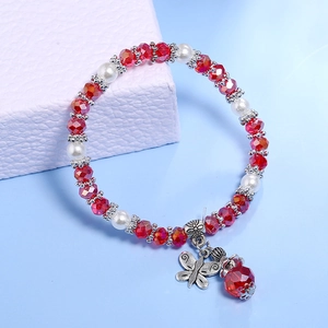 Detail eines Perlenarmbands mit silbernem Schmetterlingsanhänger und roten Kristallperlen