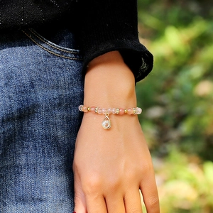 Chic pink beaded crystal bracelet with gold accents shown on wrist against green background
