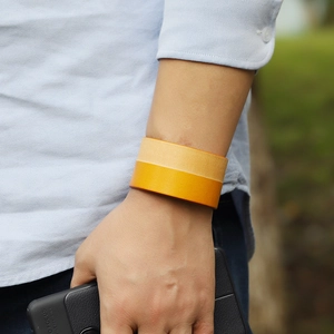 Men's minimalist dual-tone wide leather bracelet in light brown and yellow on wrist