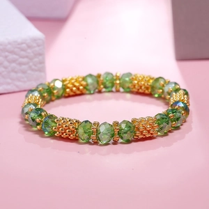 Detailed shot of faceted green crystal beads and textured gold spacers on a stretch bracelet