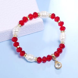 Detalle de pulsera con cuentas de cristales rojos, perlas barrocas y detalles dorados
