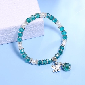 Detail eines Boho-Armbands mit grünen Kristallen, Perlen und silbernem Schmetterlingsanhänger