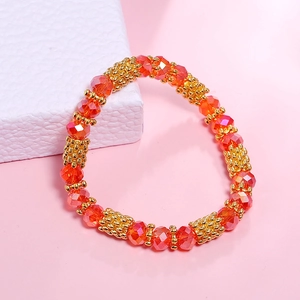 Detail view of faceted orange crystal beads with textured gold metal spacers on elastic cord