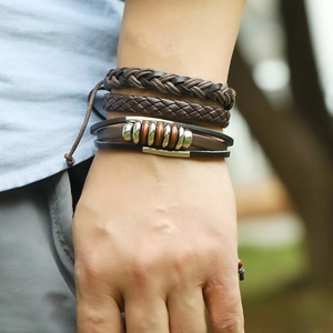 Dettaglio di set di bracciali in pelle intrecciata vintage con perline in legno al polso