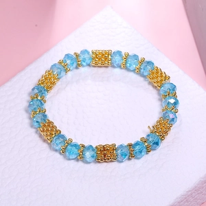 Detail showing faceted light blue crystal beads and golden textured metal spacers of the bracelet