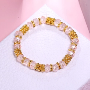 Detail of pink faceted crystal beads and textured gold metal spacers on elastic bracelet