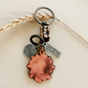 Detail of vintage braided leather keychain with engraved bronze metal tag on white background