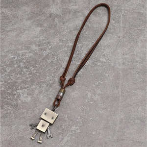 Collier pendentif robot industriel vintage avec cordon en cuir brun sur fond de pierre