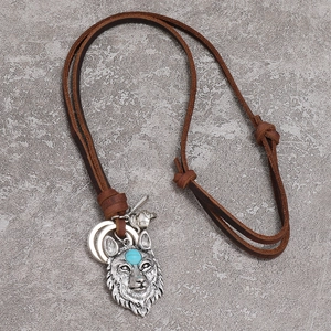 Retro wolf head necklace with turquoise inlay and leather cord on stone background