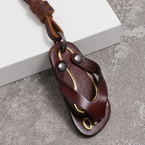 Macro detail of dark brown leather flip-flop pendant with metal rivets and vintage cord