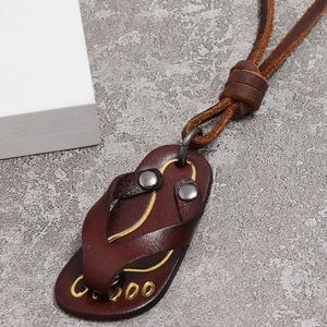 Macro detail of retro leather flip-flop pendant on necklace with gold metallic accents