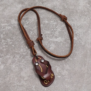 Retro brown leather flip-flop pendant necklace with yellow stitching on stone background