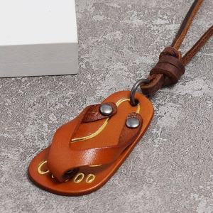 Close-up of brown leather flip-flop pendant with metal rivets and dark leather cord