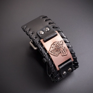Macro shot of Viking wolf totem relief on bronze plate with black braided leather strap