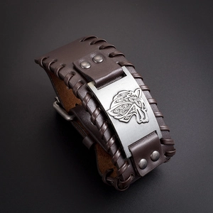 Macro shot of Viking wolf totem engraved on dark brown braided leather bracelet