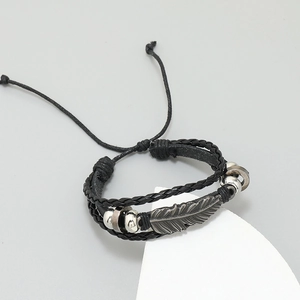 Close-up of multilayer braided leather bracelet with silver feather and beads details