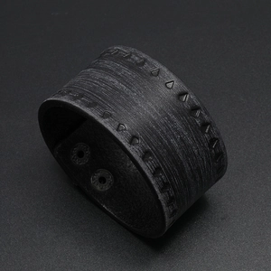 Close-up of black retro punk wide leather bracelet with embossed triangle patterns