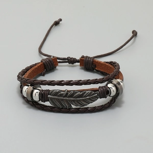 Detail of multi-layer brown leather bracelet with metal feather charm and adjustable cord