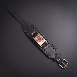 Macro detail of the wolf head totem on a black braided leather Viking bracelet