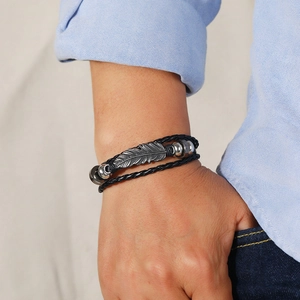 Macro shot of men's vintage braided leather bracelet with a metal feather charm