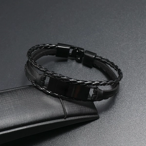 Détail d'un bracelet multicouche en cuir noir tressé avec plaque en métal poli et fermoir