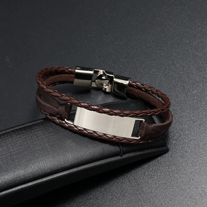 Détail d'un bracelet multicouche en cuir tressé marron avec plaque métallique argentée