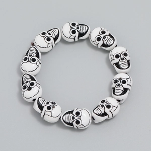 Minimalist resin skull beaded bracelet with 12 white gothic beads on gray background