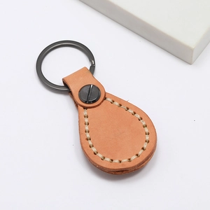 Gros plan d'un porte-clés en cuir marron vintage fait main avec surpiqûres et anneau en métal