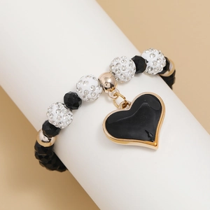 Minimalist beaded crystal bracelet with black enamel heart pendant on white stand