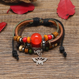 Multilayer leather beaded bracelet with butterfly pendant on rustic wood background