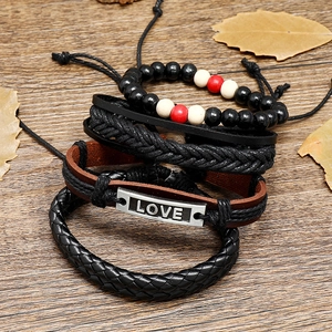Detail of vintage four-piece layered bracelet set with LOVE charm on rustic wood background