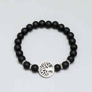Macro shot of matte black beaded bracelet featuring a silver tree of life metal charm